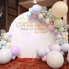 A balloon garland arch featuring pastel balloons in shades of blue, pink, and cream arranged around a white sign.