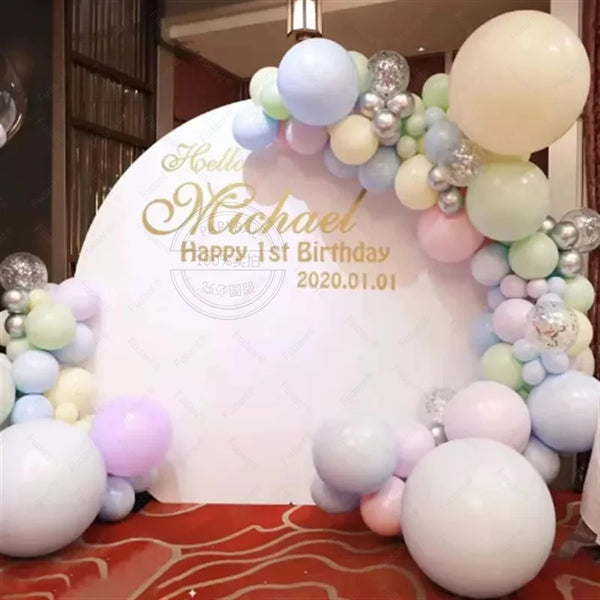 A balloon garland arch featuring pastel balloons in shades of blue, pink, and cream arranged around a white sign.