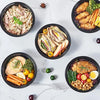 A variety of healthy meal prep foods including sliced meat, vegetables, and grains are displayed in black round containers on