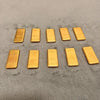 A set of ten simulated gold ingot fortune charms arranged in a row on a gray surface.