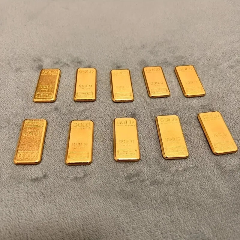 A set of ten simulated gold ingot fortune charms arranged in a row on a gray surface.