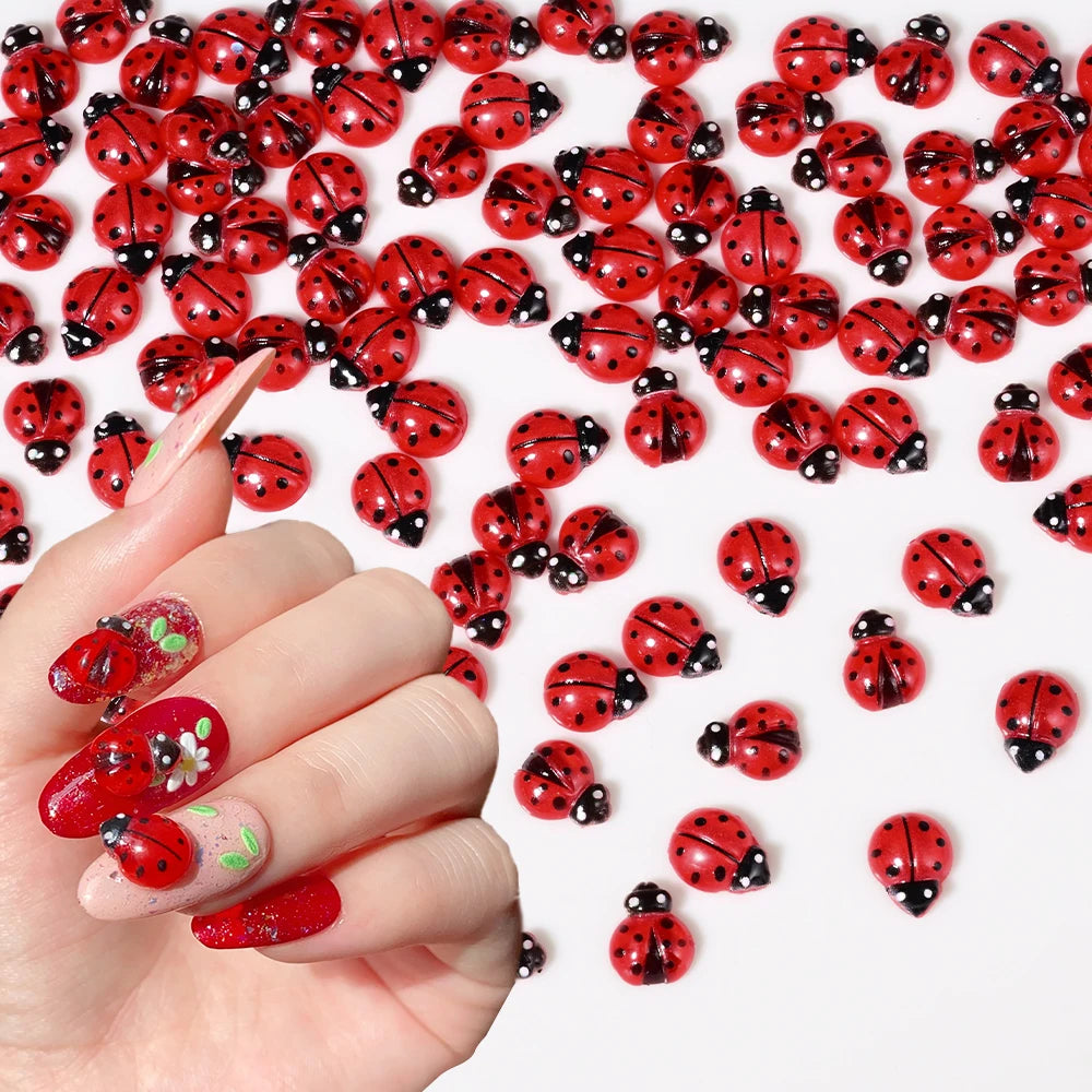 A hand displays a collection of red and black ladybug resin nail art charms on a white background.