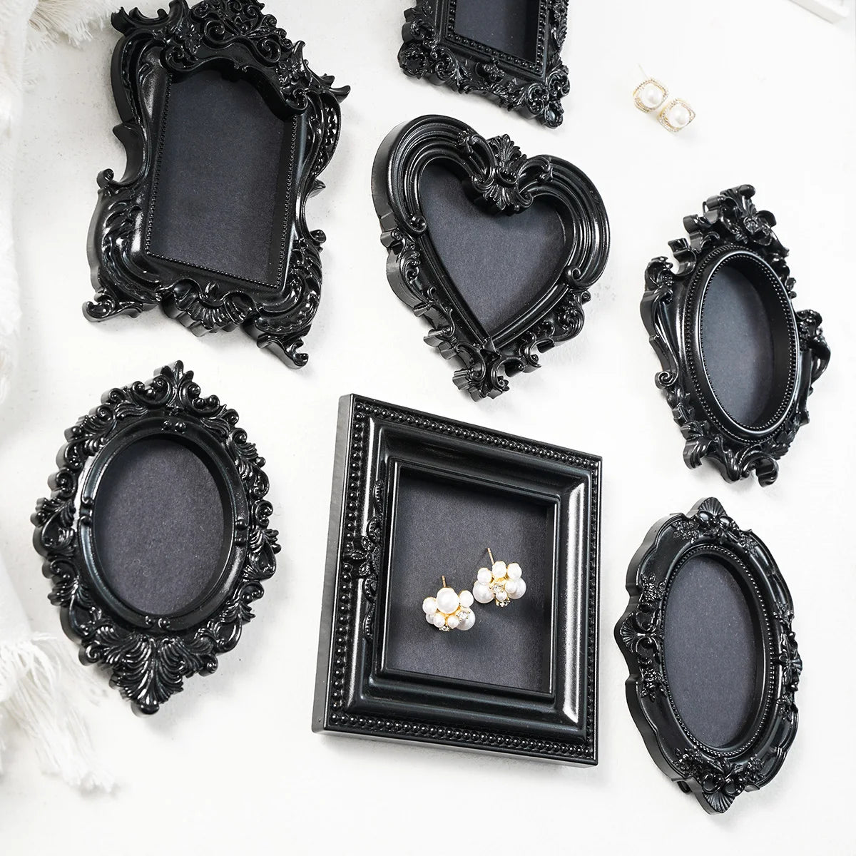 A collection of black ornate picture frames and decorative mirrors with gold accents on a white background.