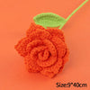 Handmade orange crochet rose flower with a green leaf on an orange background