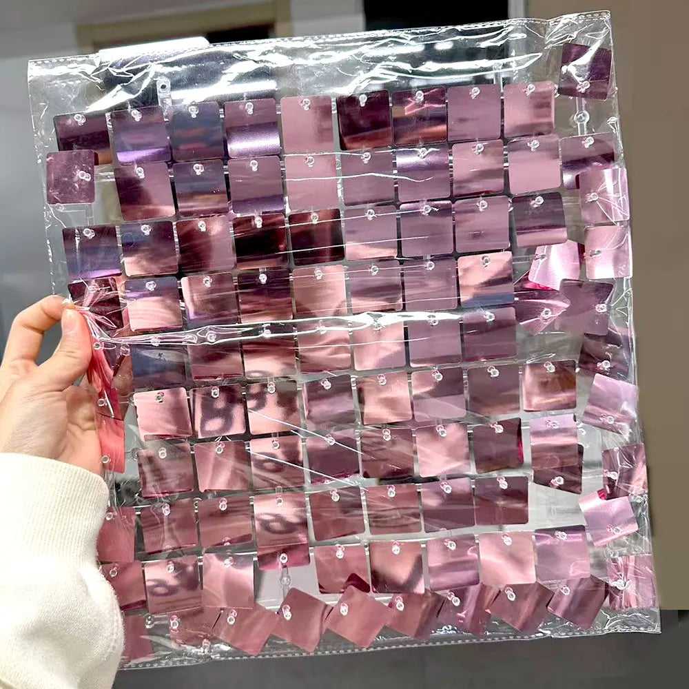 A clear plastic bag filled with square pink shimmer sequins used as wall backdrop panels for party decor.