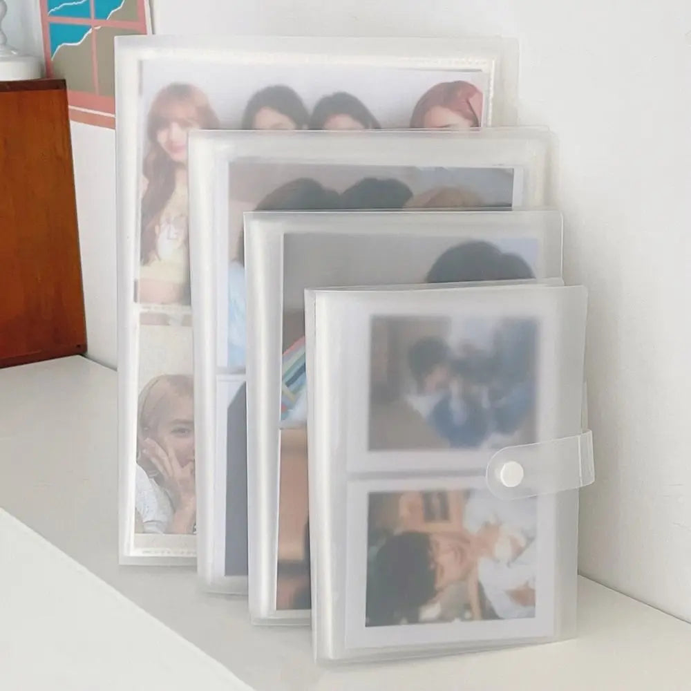 A stack of clear photo albums with transparent card holders displaying various portraits.