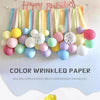 Buntes Display aus zerknitterten Papierstreifen in Pastelltönen vor weißem Hintergrund.
