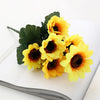 A bouquet of bright yellow artificial sunflowers on a white surface.