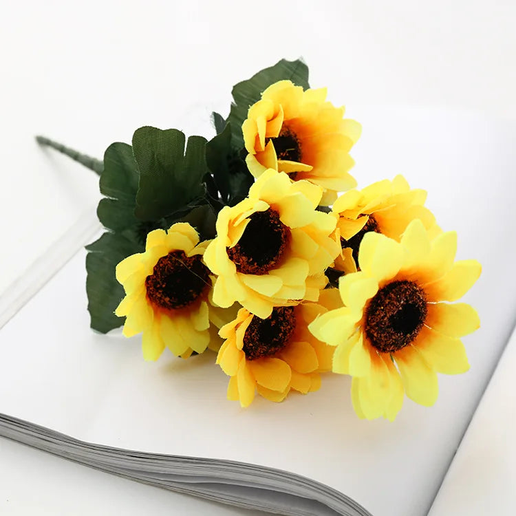 A bouquet of bright yellow artificial sunflowers on a white surface.