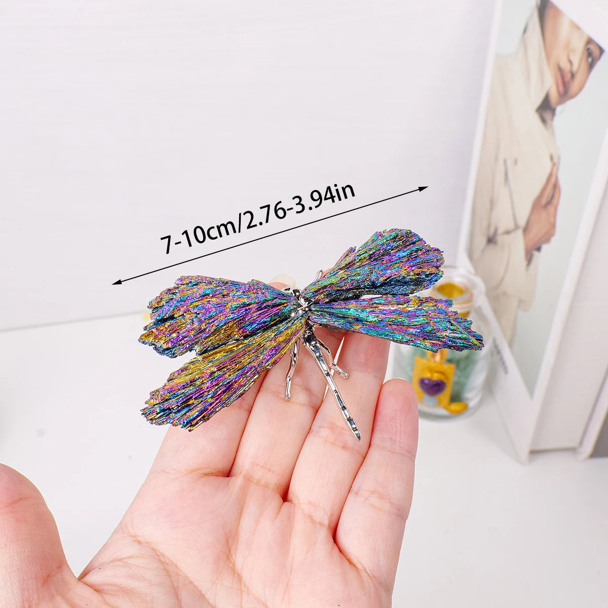 A hand holds a sparkling natural crystal tourmaline dragonfly figurine with a 7-10cm length.