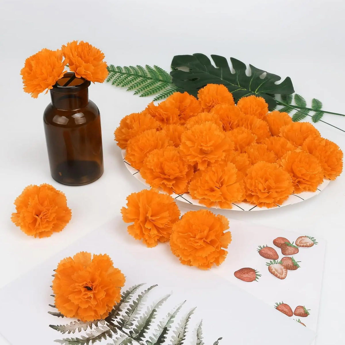 A collection of bright orange silk marigold flowers used for Dia de los Muertos and fall decor, displayed with green foliage.