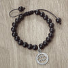 A black beaded bracelet with a silver pendant featuring a mountain design.