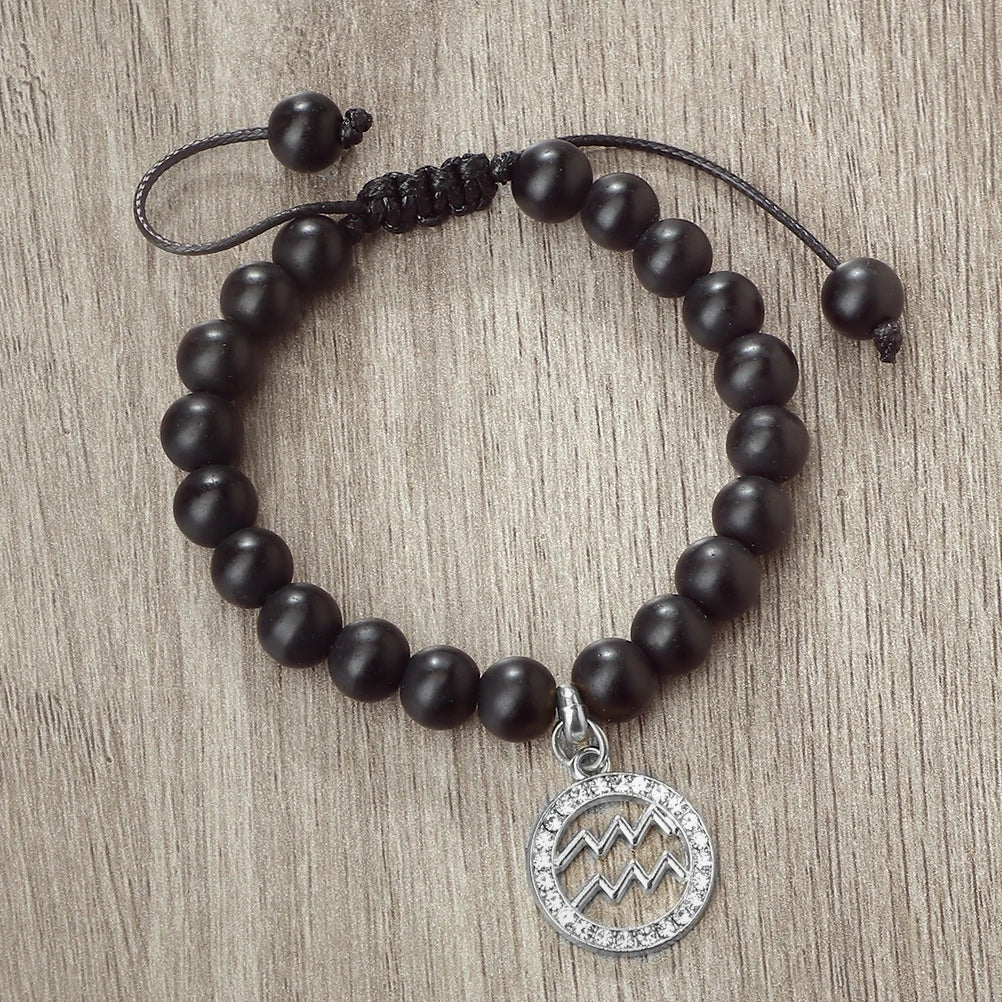 A black beaded bracelet with a silver pendant featuring a mountain design.