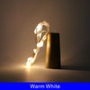 A single LED wine bottle cork light illuminates a dark amber glass bottle.