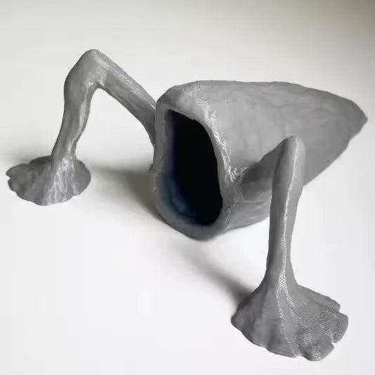A gray 3D printed articulated sea monster fidget toy with elongated limbs and a large open mouth.