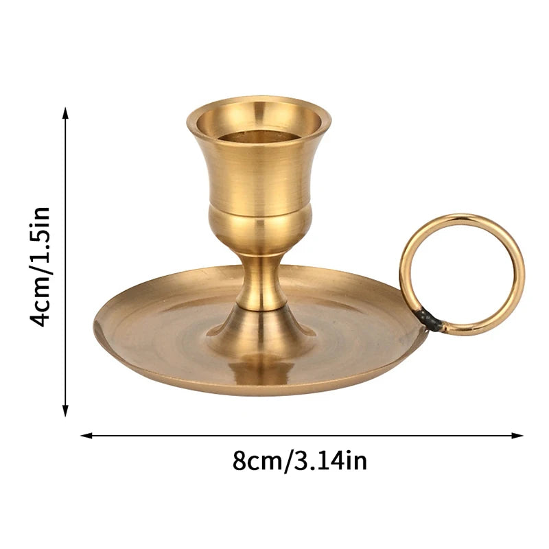 A brass metal candle holder with a flared base and a circular handle for table settings.