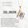 A silver pendant necklace featuring an openable book design with engraved text on a gold chain.