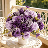 A vibrant bouquet of artificial mixed flowers featuring purple and lavender roses, daisies, and chrysanthemums displayed on a