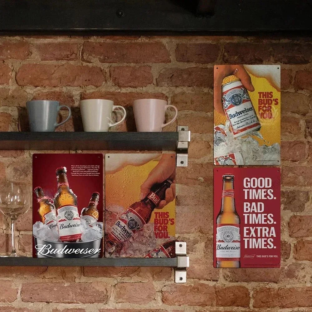 A set of vintage beer metal signs featuring Budweiser branding displayed on a rustic brick wall.
