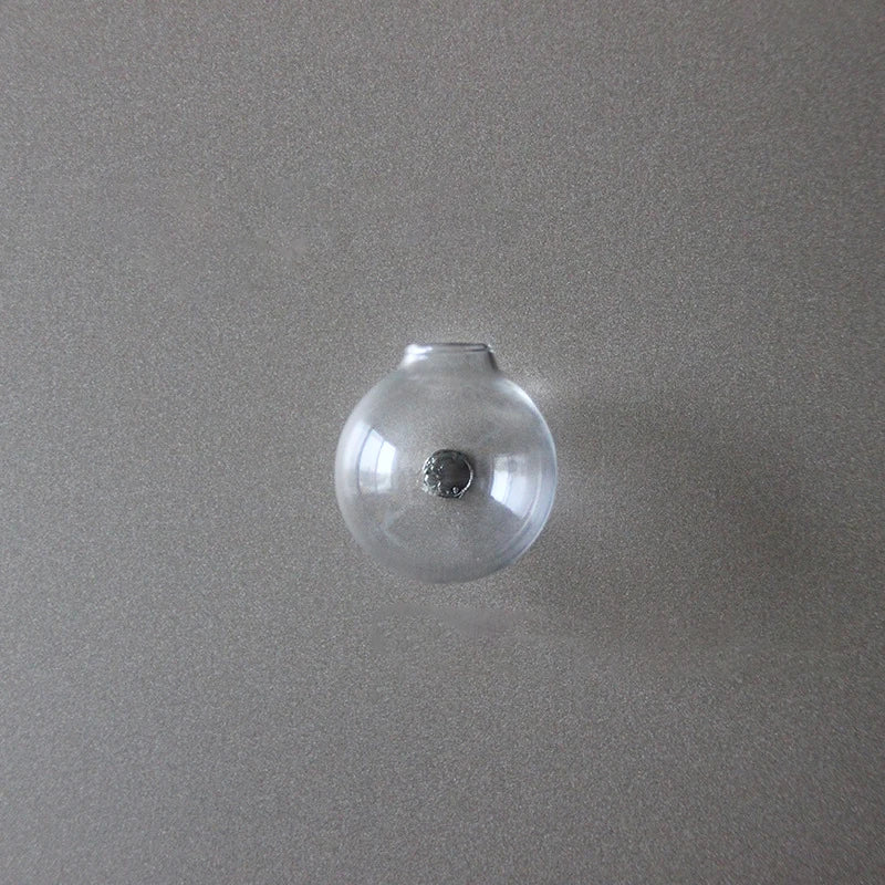 A clear glass spherical fridge magnet with a silver stud in the center.