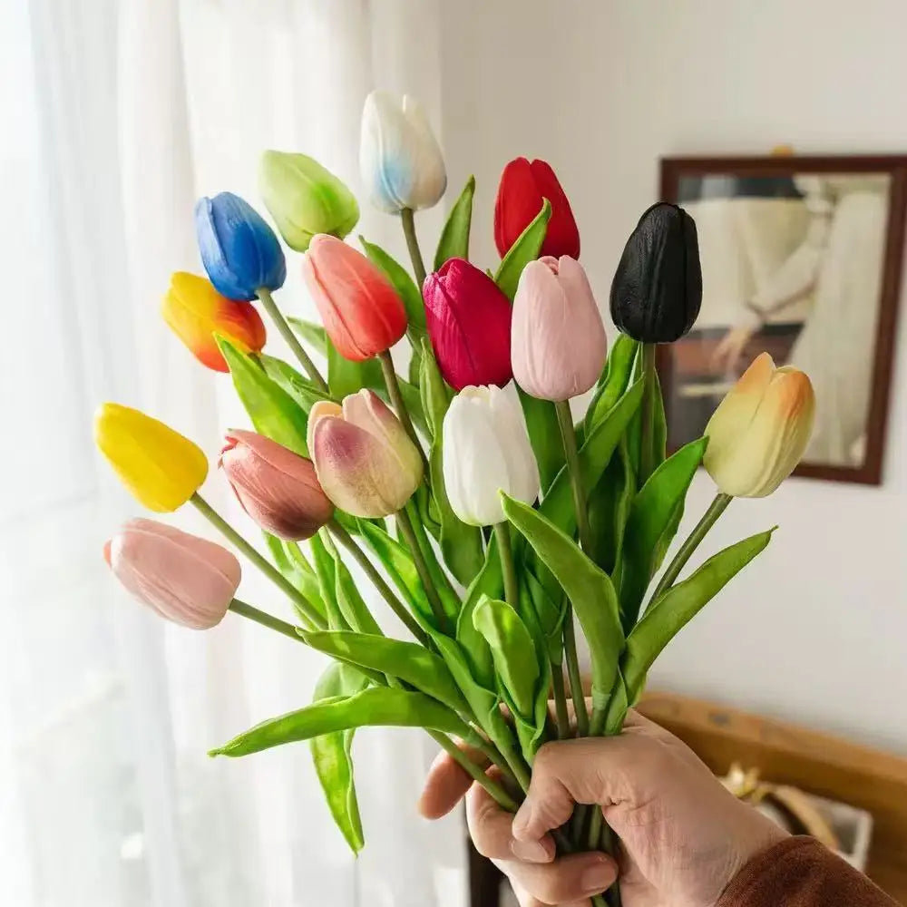 A bouquet of colorful artificial tulips in shades of pink, yellow, red, and purple held by a hand.