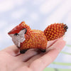Hand-painted resin fox totem statue with orange and white fur resting in a person's hand.