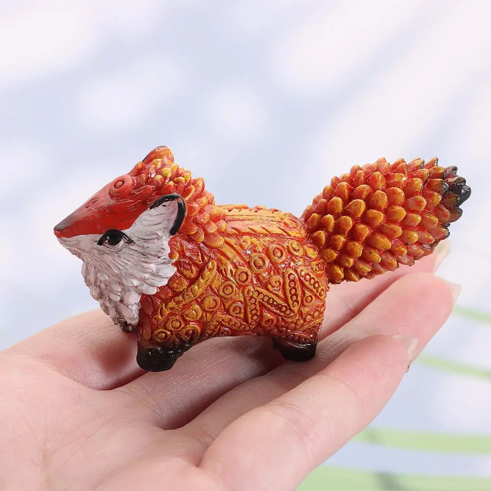 Hand-painted resin fox totem statue with orange and white fur resting in a person's hand.