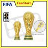 A gold FIFA 2026 World Cup trophy fridge magnet shown next to its packaging and a close-up of the magnetic suction part.
