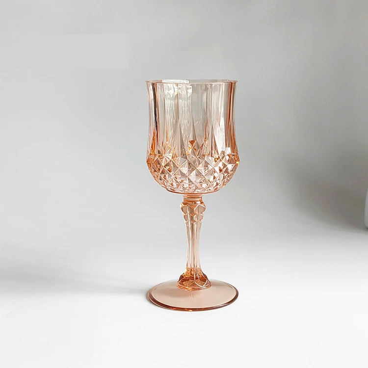 A clear, textured, rose gold colored plastic wine glass with a stem and foot.