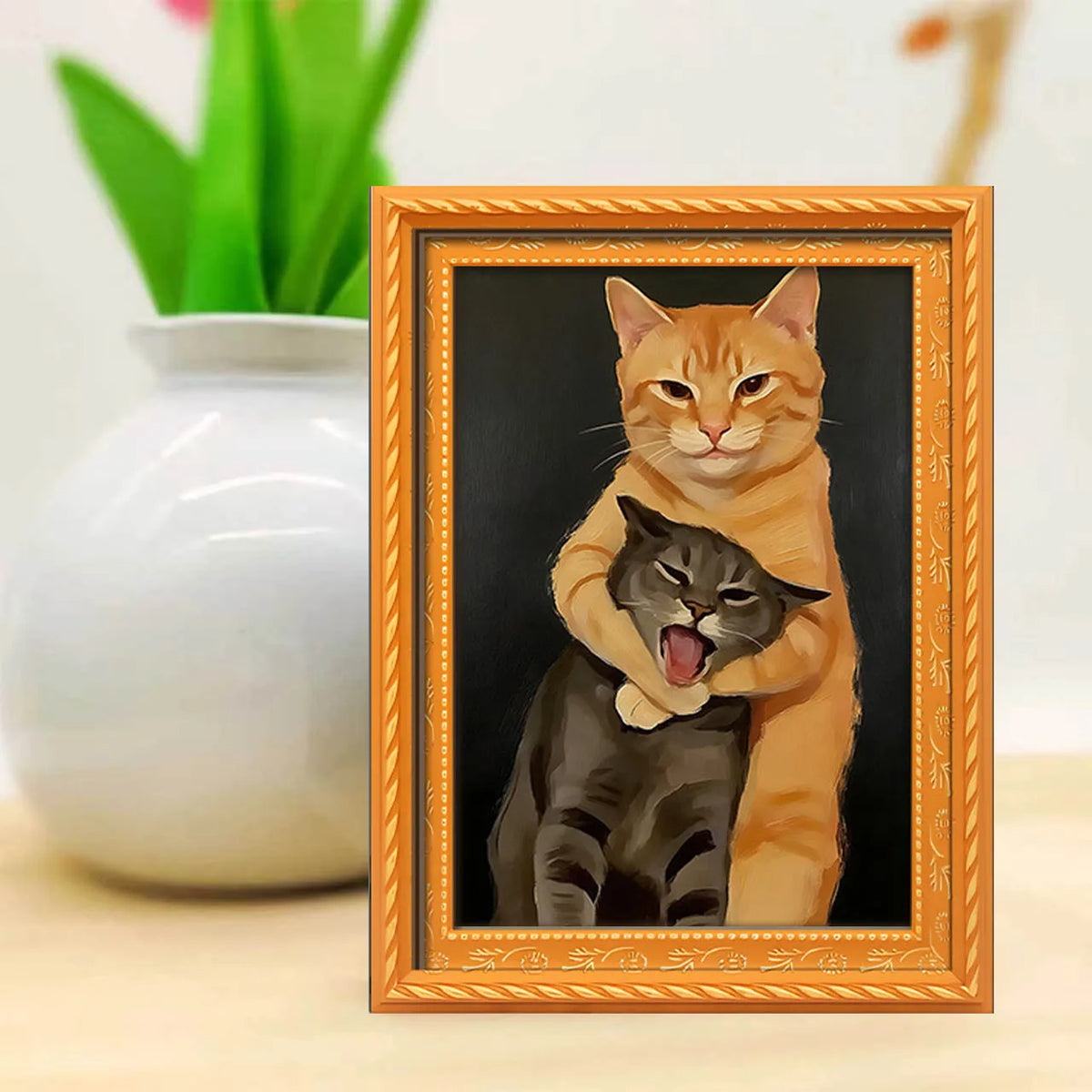 A framed painting depicting an orange cat hugging a black cat, set against a dark background.