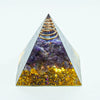 A clear quartz pyramid with purple amethyst crystals and a gold coil at the apex.