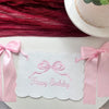 Pink decorative birthday garland with a bow and the text Happy Birthday on white paper