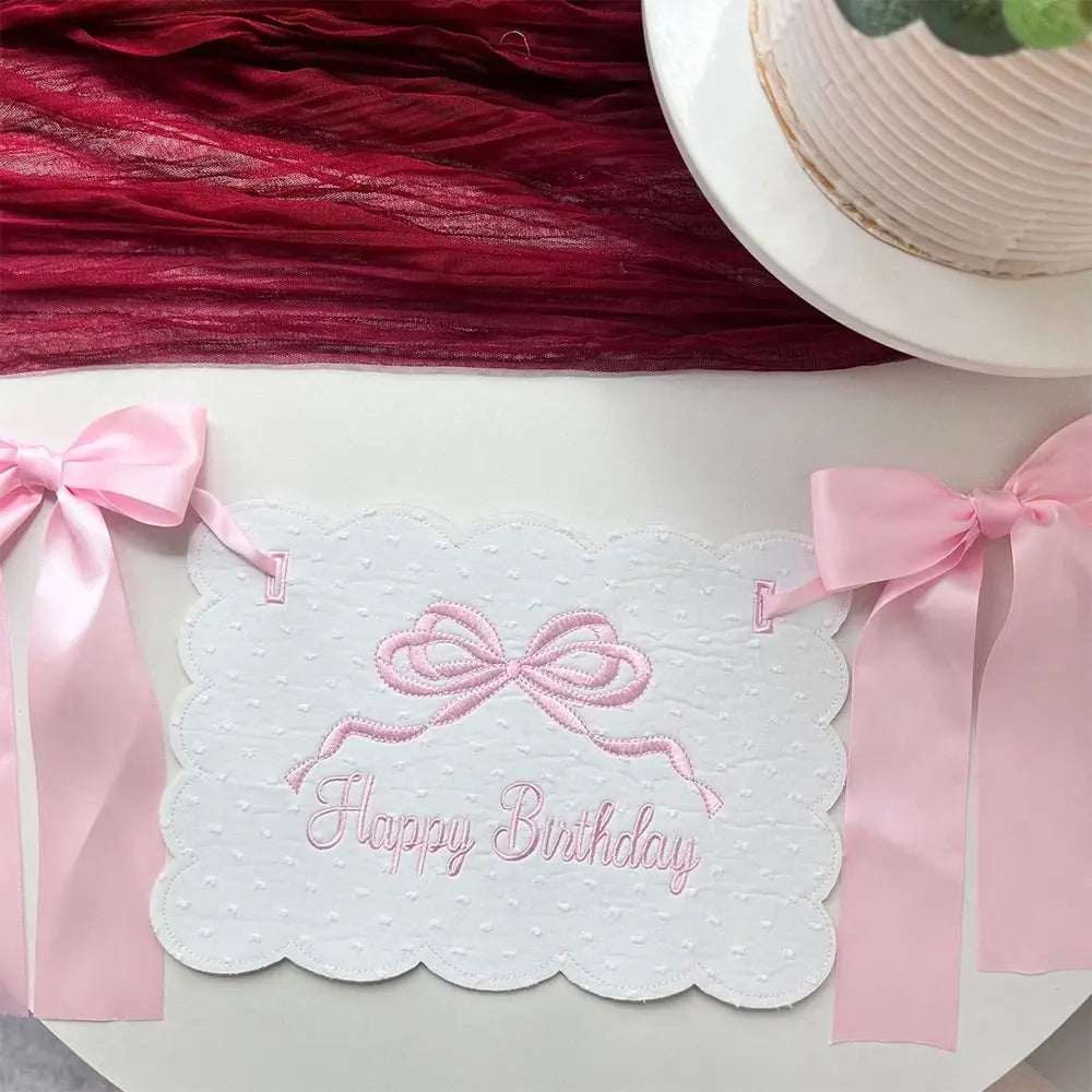 Pink decorative birthday garland with a bow and the text Happy Birthday on white paper