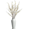 A branch of real touch faux plum blossoms with stems in a white vase.