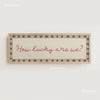 A framed canvas print with a light background and pink and green borders featuring the text How lucky are we?