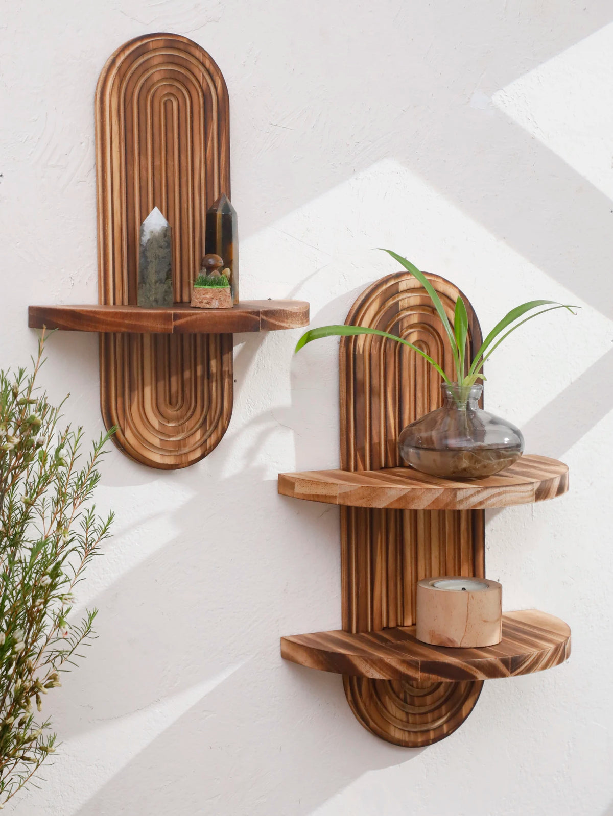 Two wooden wall shelves with natural wood slats display small stones and a green plant.