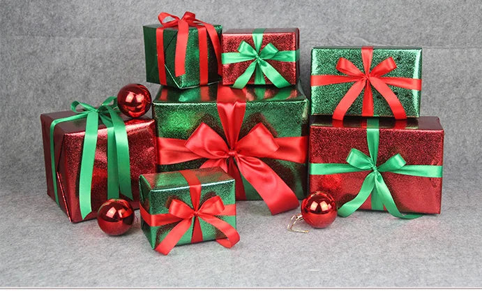 A collection of green and red gift boxes tied with satin ribbons and adorned with shiny red ornaments.