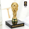 A gold FIFA World Cup 2026 trophy figurine displayed on a black square base.