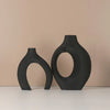A set of two matte black, organic-shaped vases displayed against a light beige background.