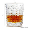 A clear whiskey glass with a diamond-cut pattern and a heavy base, showing an amber liquid.