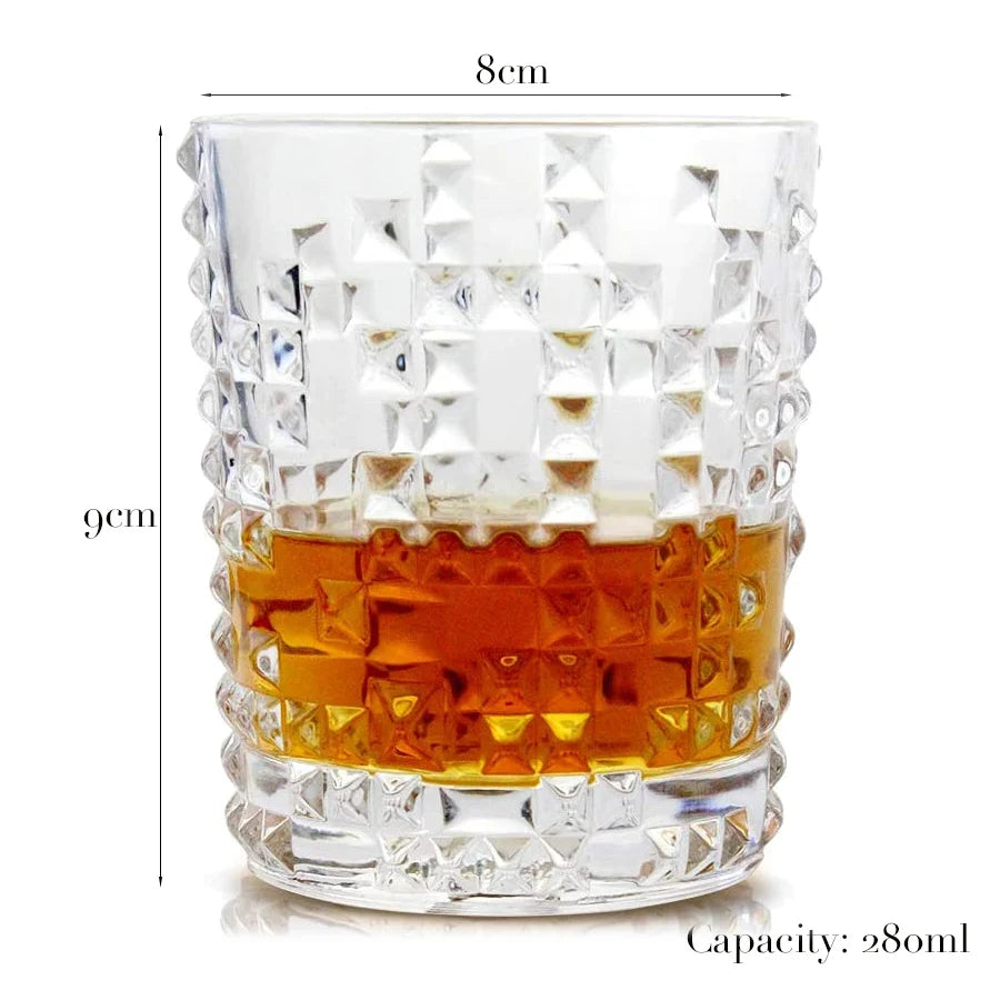 A clear whiskey glass with a diamond-cut pattern and a heavy base, showing an amber liquid.