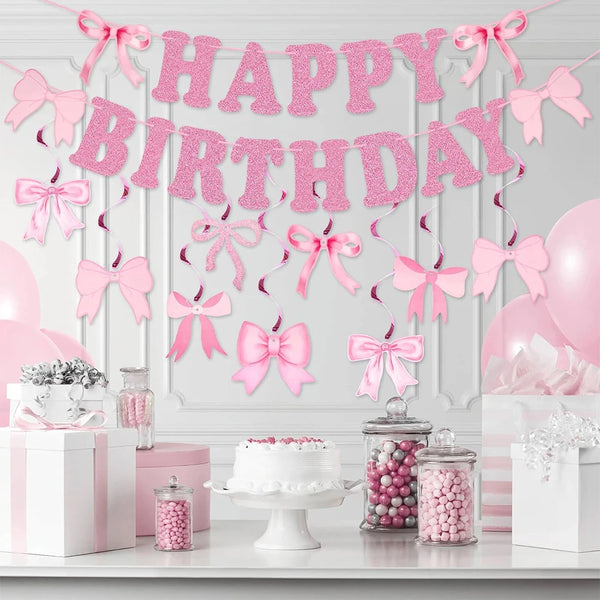 Glitter pink bow birthday banner strung across a white wall with pink balloons and gift boxes