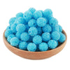 A pile of bright blue textured resin beads for jewelry making in a wooden bowl.