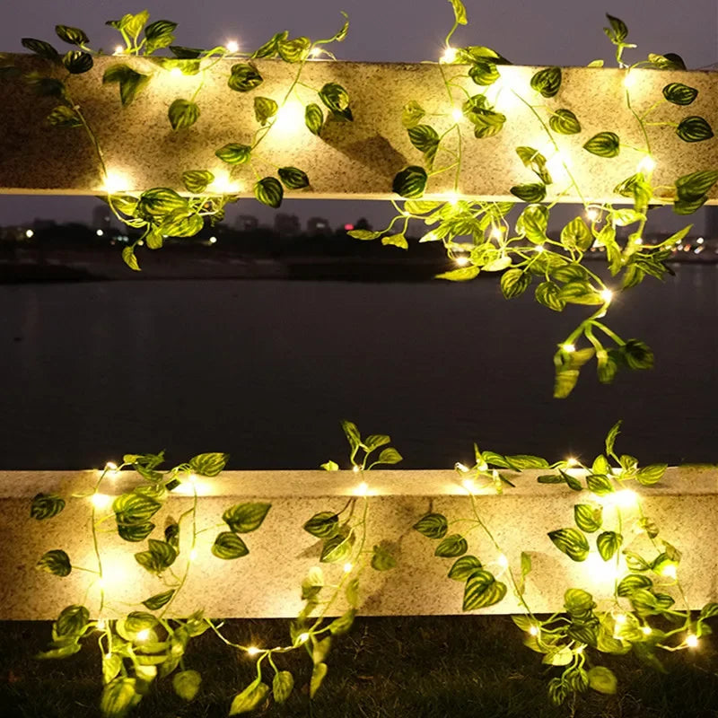 Golden string lights shaped like leaves illuminate a horizontal structure in an outdoor setting.
