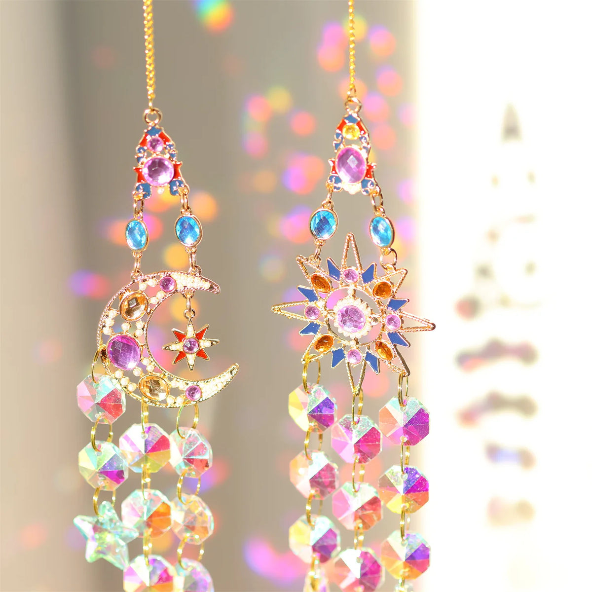 A pair of hanging crystal sun and moon charms featuring iridescent glass beads and gold accents.