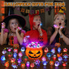 A collection of glowing Halloween rings and pumpkin-themed lights displayed on a wooden surface.