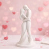 A white minimalist sculpture of a couple hugging, set against a soft pink background with bokeh lights.