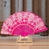 A vibrant pink lace folding hand fan with intricate floral patterns displayed on a wooden stand.
