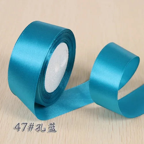 A roll of teal silk satin ribbon used for gift wrapping and craft projects.