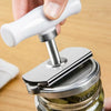 A hand is using a stainless steel multi-function bottle cap opener to open a glass jar.